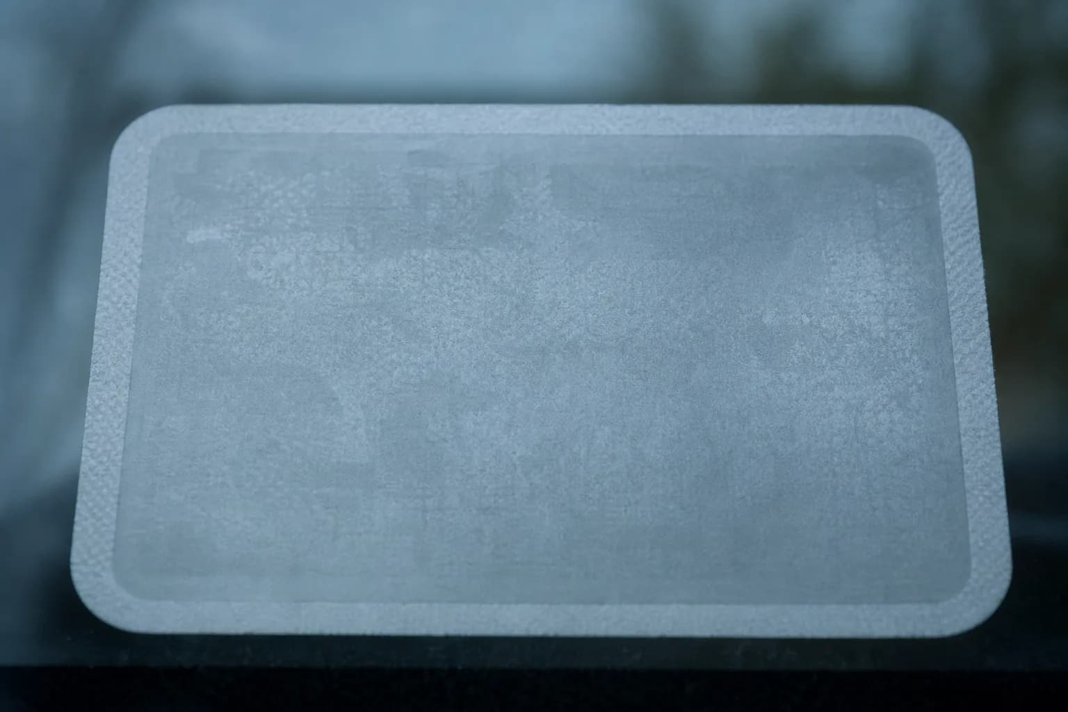 A close-up of an unbranded car registration sticker on a windshield in cool morning light.